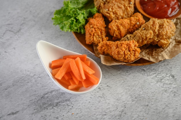 Pollo frito crujiente en un plato con salsa de tomate y zanahoria