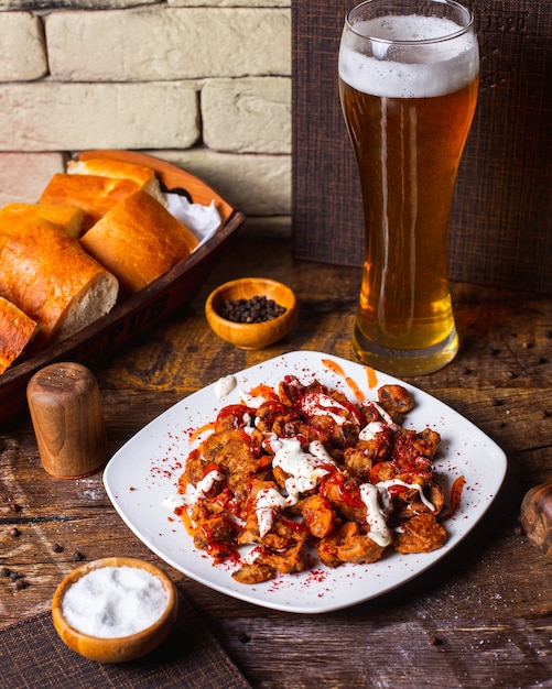 Pollo frito crujiente servido con salsa y cerveza