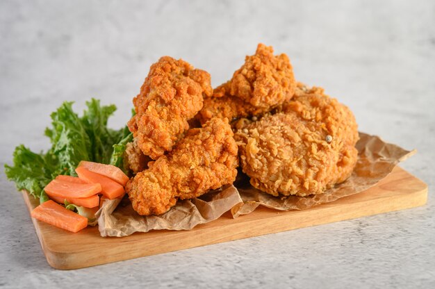 Pollo frito crujiente sobre una tabla para cortar madera