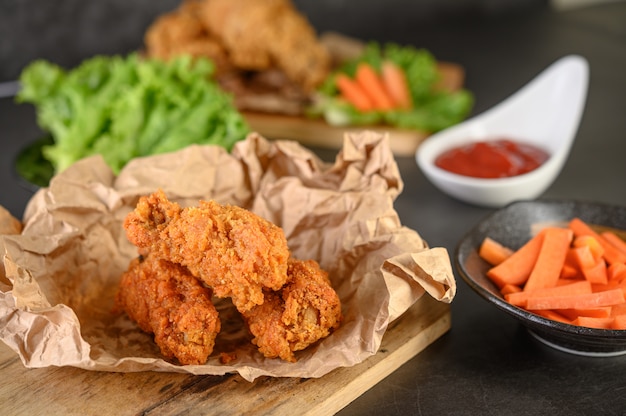 Pollo frito crujiente sobre una tabla de cortar con salsa de tomate y zanahoria