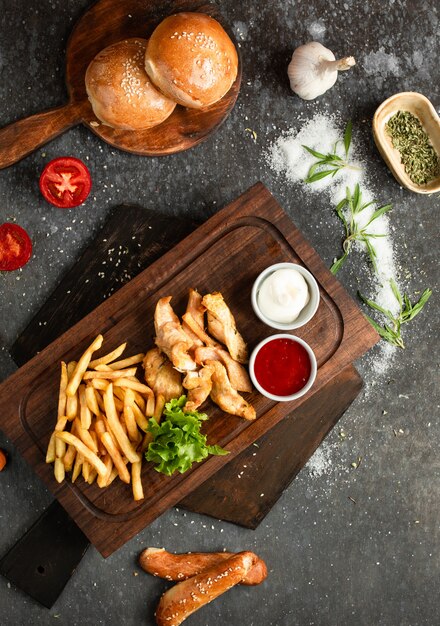 Pollo frito y papas fritas en una tabla de madera
