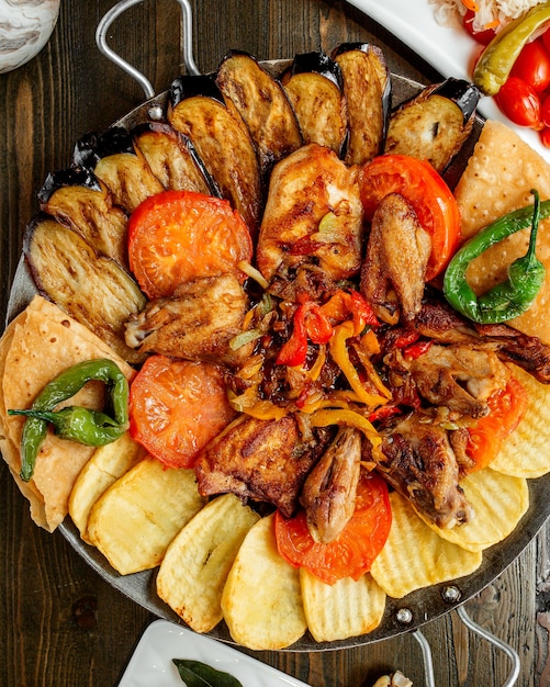 Pollo frito con papas a la parrilla, berenjenas, tomates y pimientos.