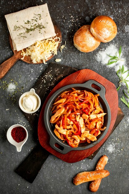 Pollo frito con pimiento y cebolla en una sartén de aluminio