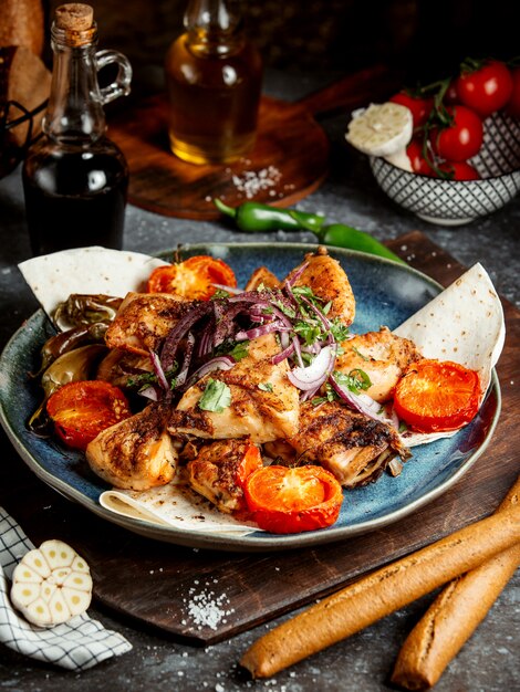 Pollo frito con rodajas de tomate y cebolla.