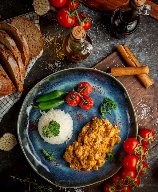 Pollo frito en salsa y arroz con verduras.