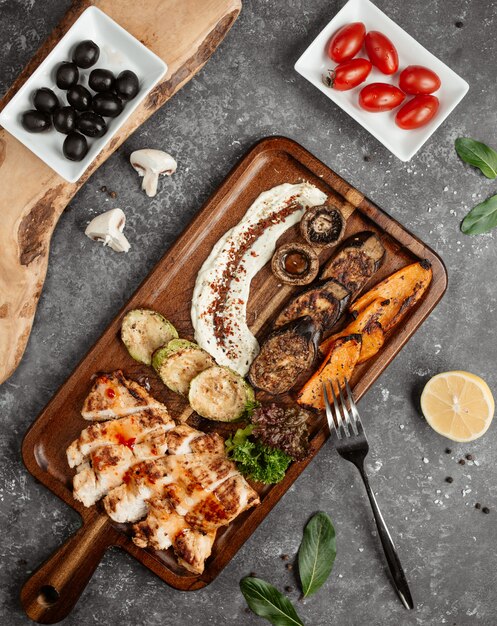 Pollo frito con verduras sobre una plancha de madera