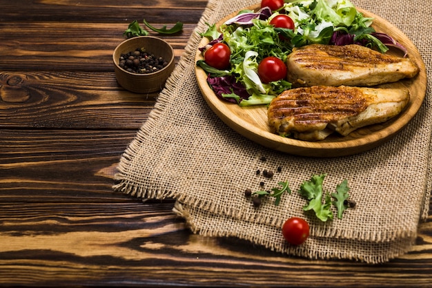 Foto gratuita pollo a la parrilla y ensalada cerca de pimienta negra