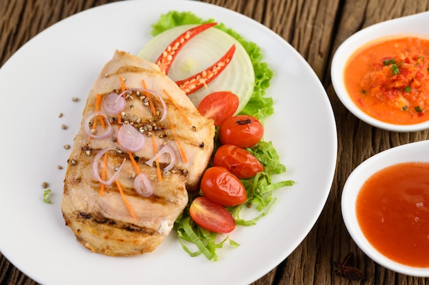 Foto gratuita pollo a la parrilla en un plato blanco con tomate, ensalada, cebolla, chile y salsa.