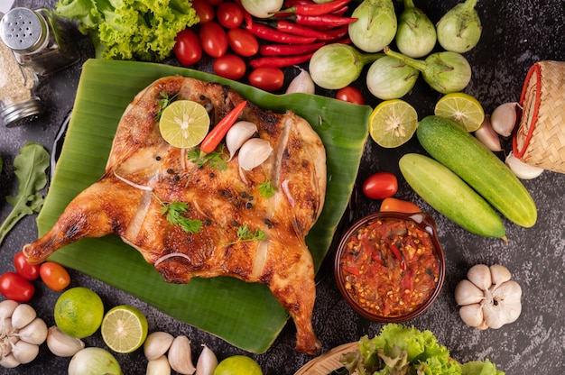 Pollo a la parrilla en un plato con chiles, salsa de ajo y espolvoreado con semillas de pimiento.