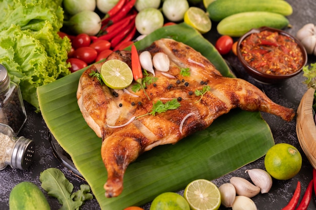 Pollo a la parrilla en un plato con chiles, salsa de ajo y espolvoreado con semillas de pimiento.