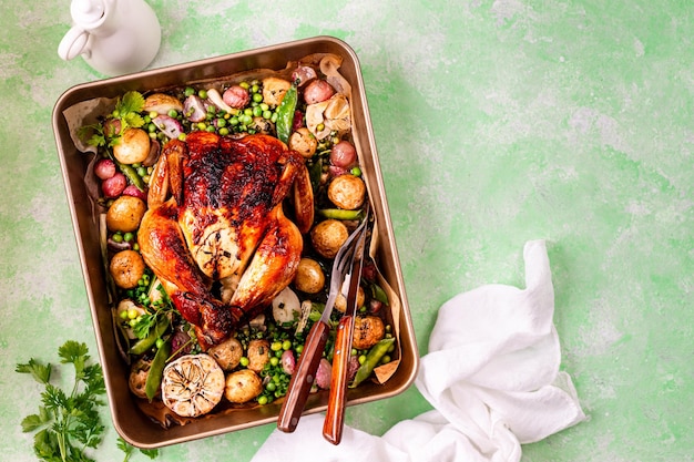 Foto gratuita pollo de primavera horneado con rábanos y guisantes verdes en una olla sobre un fondo verde