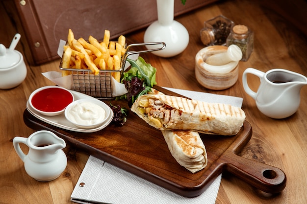 pollo shawarmin hoyo con papas fritas salsa de tomate mayonesa y lechuga en la mesa