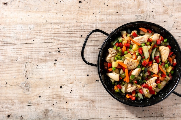 Pollo y verduras en mesa de madera rústicaCopiar espacio