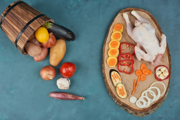 Un pollo con verduras sobre una tabla de madera.