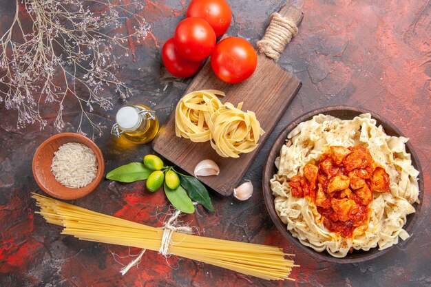 Pollo de vista superior con plato de pasta de masa con tomates en comida de pasta de masa de superficie oscura