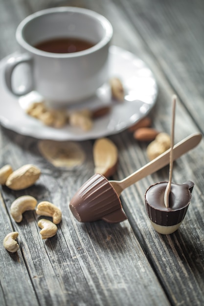Polo de chocolate en forma de una pequeña taza con una taza de té y nueces sobre madera