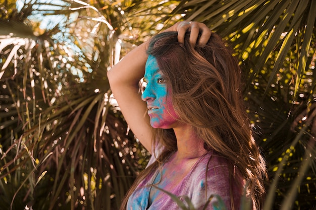 Foto gratuita polvo de color holi azul y rojo en la cara de la mujer mirando a otro lado