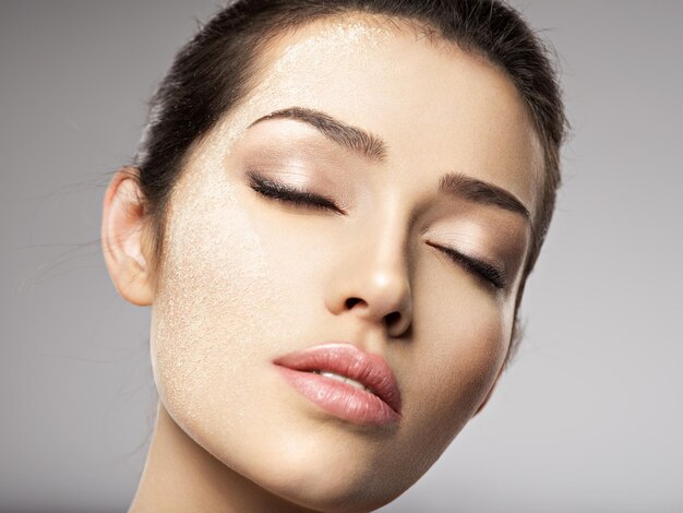 El polvo de maquillaje cosmético seco está en el rostro femenino. Concepto de tratamiento de belleza. Chica hace maquillaje.