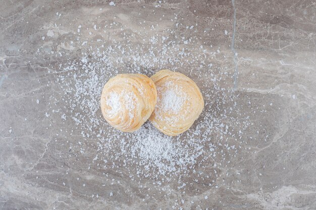 Polvo de vainilla y dos galletas escamosas sobre superficie de mármol