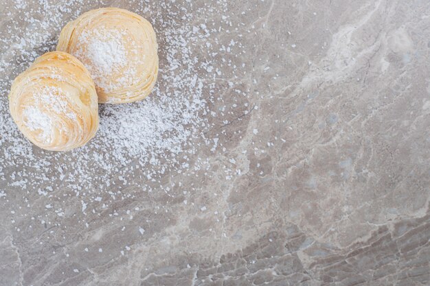 Polvo de vainilla y dos galletas escamosas sobre superficie de mármol