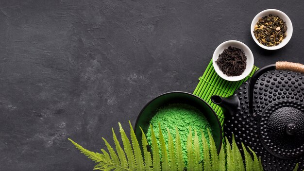 Polvo verde del té del matcha con la hierba seca en fondo negro
