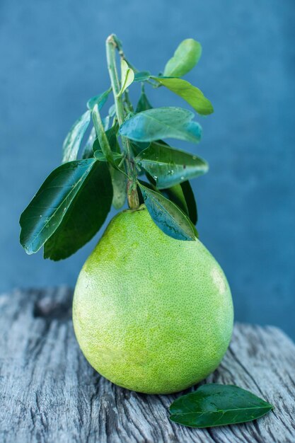 Pomelo con hojas verdes sobre una tabla de madera