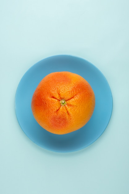 Pomelo naranja una vista superior fresca jugosa dentro de la placa azul y en el piso azul hielo