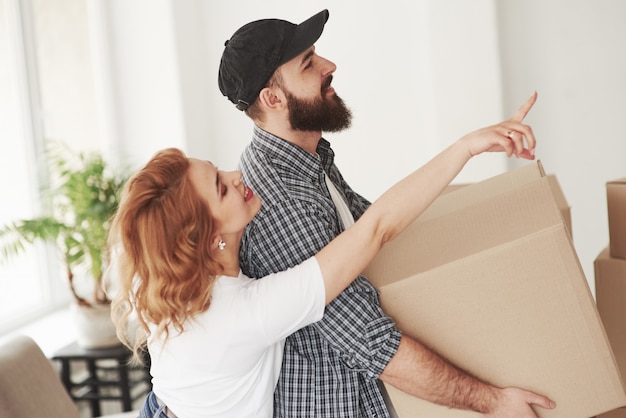 Pon esto ahí. Pareja feliz juntos en su nueva casa. Concepción de mudanza