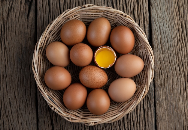 Foto gratuita pon los huevos en una canasta de madera sobre un piso de madera.