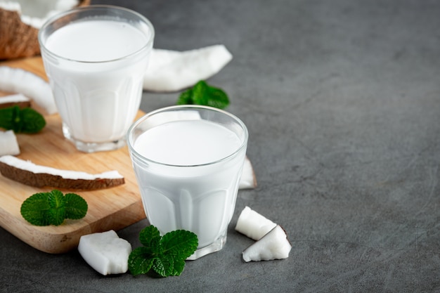 Poner dos vasos de leche de coco sobre fondo oscuro