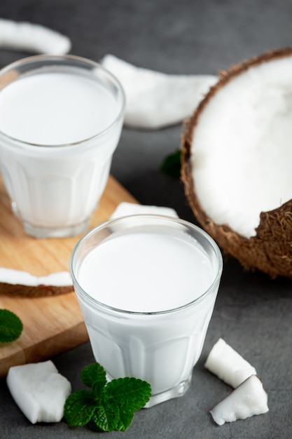 Poner dos vasos de leche de coco sobre fondo oscuro