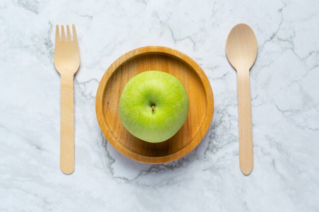 Poner las manzanas verdes en un cuenco de madera junto a una cuchara y un tenedor de madera