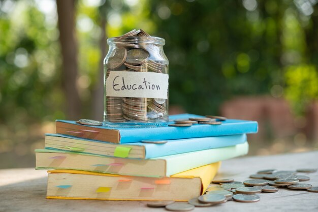 Poner monedas de dinero ahorrando en una botella de vidrio para las finanzas y negocios de fondos mutuos de inversión de concepto, colocadas en el libro de texto. contenido de ahorro de dinero para la educación.