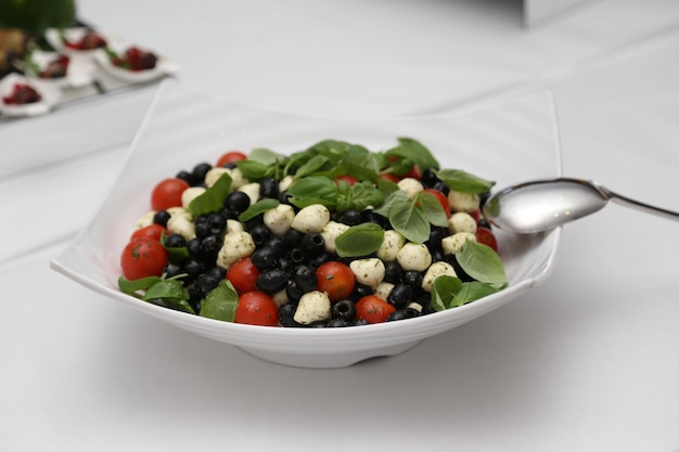 Porción de una deliciosa ensalada con tomates cherry, queso, albahaca, anolives