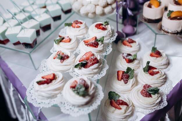 Porción de merengues decorados con menta y fresa servidos en mesa de catering