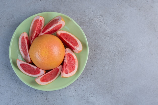 Foto gratuita una porción de pomelo en un plato sobre fondo de mármol.