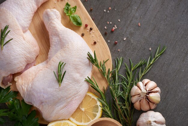 porciones de carne de pollo fresca para cocinar y asar a la parrilla con condimentos frescos. Muslo de pollo crudo crudo sobre tabla de cortar.