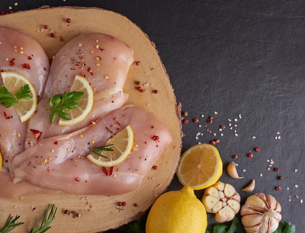 porciones de carne de pollo fresca para cocinar y asar a la parrilla con condimentos frescos. Muslo de pollo crudo crudo sobre tabla de cortar.