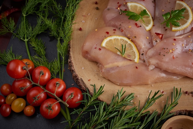 porciones de carne de pollo fresca para cocinar y asar a la parrilla con condimentos frescos. Muslo de pollo crudo crudo sobre tabla de cortar.