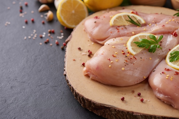 porciones de carne de pollo fresca para cocinar y asar a la parrilla con condimentos frescos. Muslo de pollo crudo crudo sobre tabla de cortar.