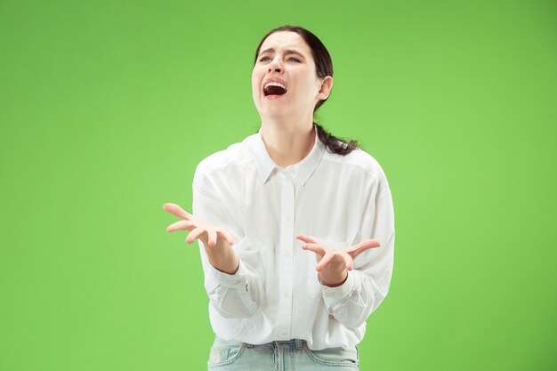 Porqué es eso. Hermoso retrato femenino de medio cuerpo aislado en el fondo de color verde moderno del estudio. Joven mujer emocional sorprendida, frustrada y desconcertada. Las emociones humanas, el concepto de expresión facial.