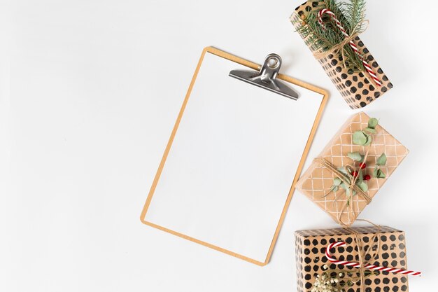 Portapapeles con pequeñas cajas de regalo en mesa de luz