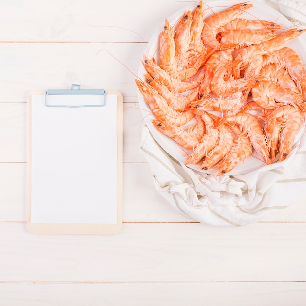 Foto gratuita portapapeles con plato de gambas en la mesa de la cocina