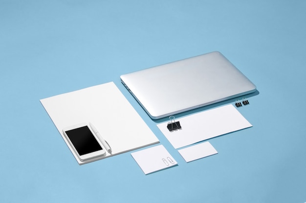 El portátil, bolígrafos, teléfono, nota con pantalla en blanco sobre la mesa