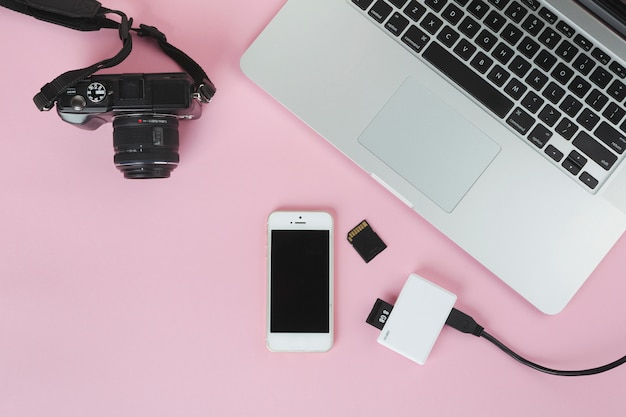 Foto gratuita portátil con cámara y tarjeta sd en mesa rosa