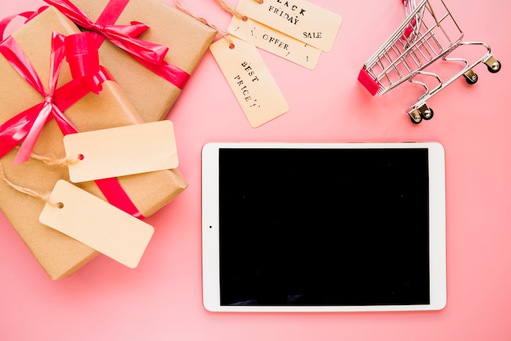 Foto gratuito portátil cerca de carrito de compras y cajas de regalo.