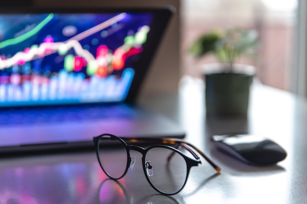 Foto gratuita portátil con gráficos y estadísticas y gafas sobre la mesa.