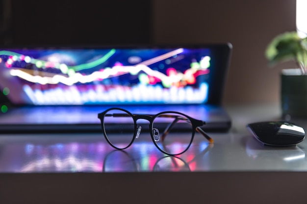 Foto gratuita portátil con gráficos y estadísticas y gafas sobre la mesa.