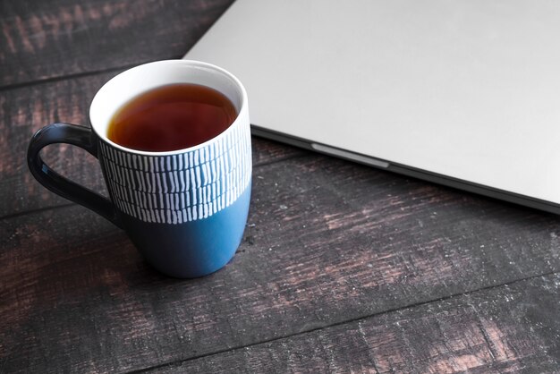 Portátil gris con café sobre mesa de madera