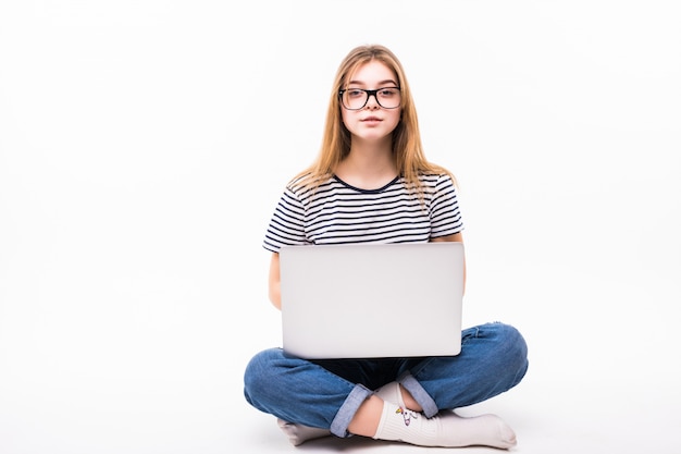 Portátil independiente o de trabajo en casa. Hermosa mujer en casual sentarse en el piso y trabajar con una computadora portátil con las piernas cruzadas